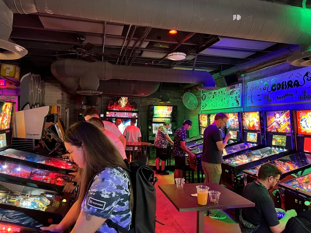 WordCamp US attendees playing pinball machines at Cobra Arcade Bar.