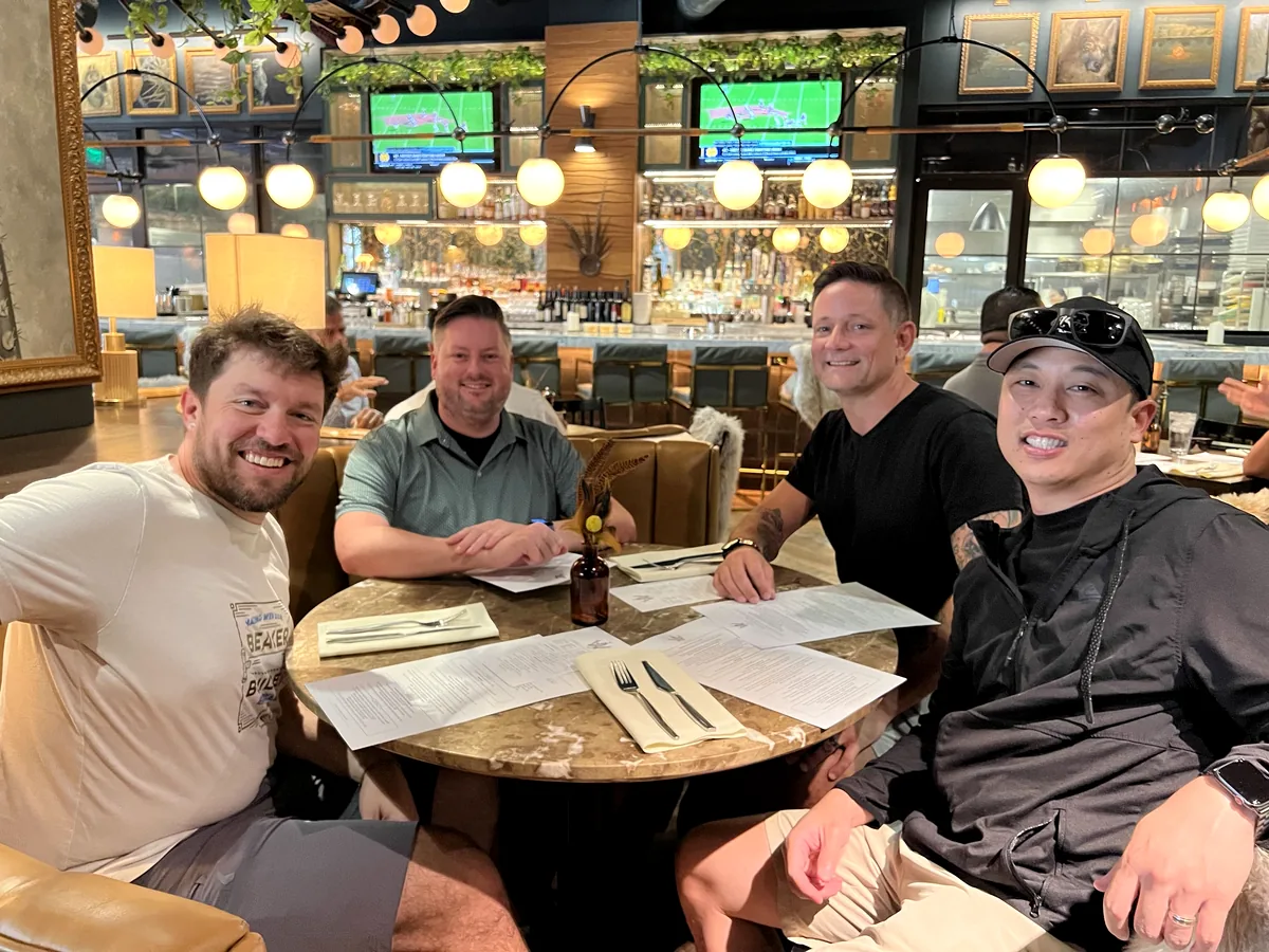 Four WordCamp US attendees smiling around a restaurant table in Phoenix.