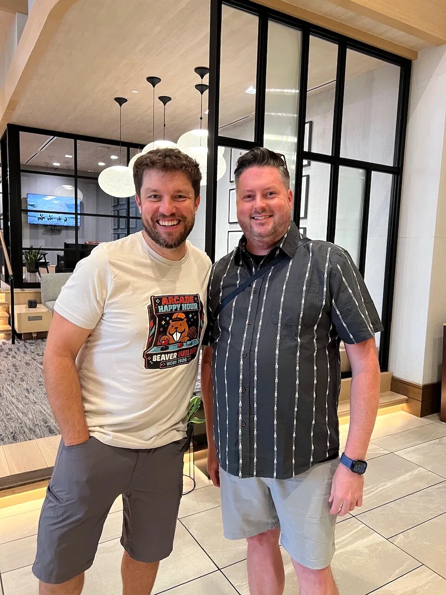 Robby and Brent smiling together while Robby wears a Beaver Builder Arcade Happy Hour shirt.