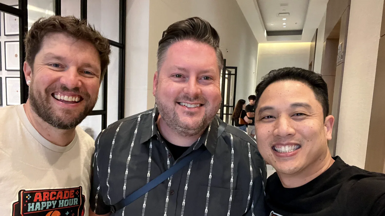 Robby, Brent, and Anthony smiling together at WordCamp US 2026, with Robby and Anthony wearing Arcade Happy Hour shirts.